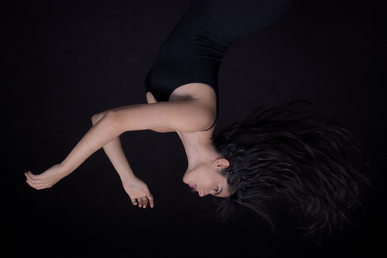 Woman lying on a black background with flowing hair and outstretched arms
